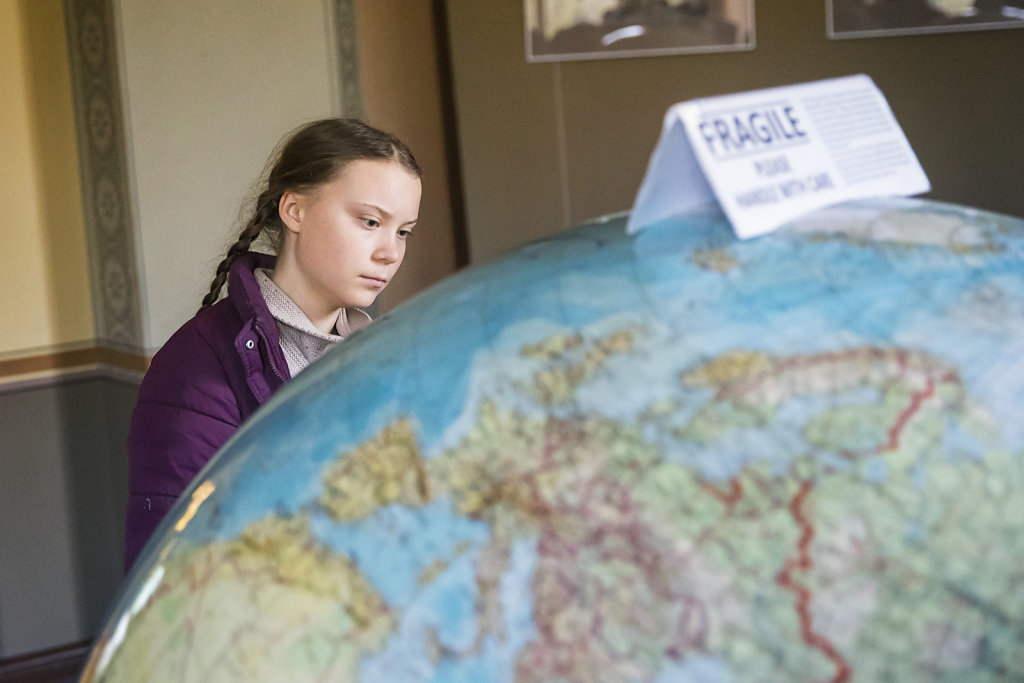 Die schwedische Klimaaktivistin Greta Thunberg betrachtet einen Globus im Potsdam-Institut f?r Klimafolgenforschung am 29. M?rz 2019. Auf dem Modell steht ein Schild mit der Warnung "Fragile please handle with care".
